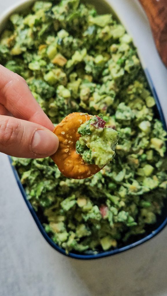 Grüner Salat mit Gurken, Erbsen, Tofu und weiteren Zutaten mit einem cremigen Dressing auf einem kleinen Laugen-Kringel.