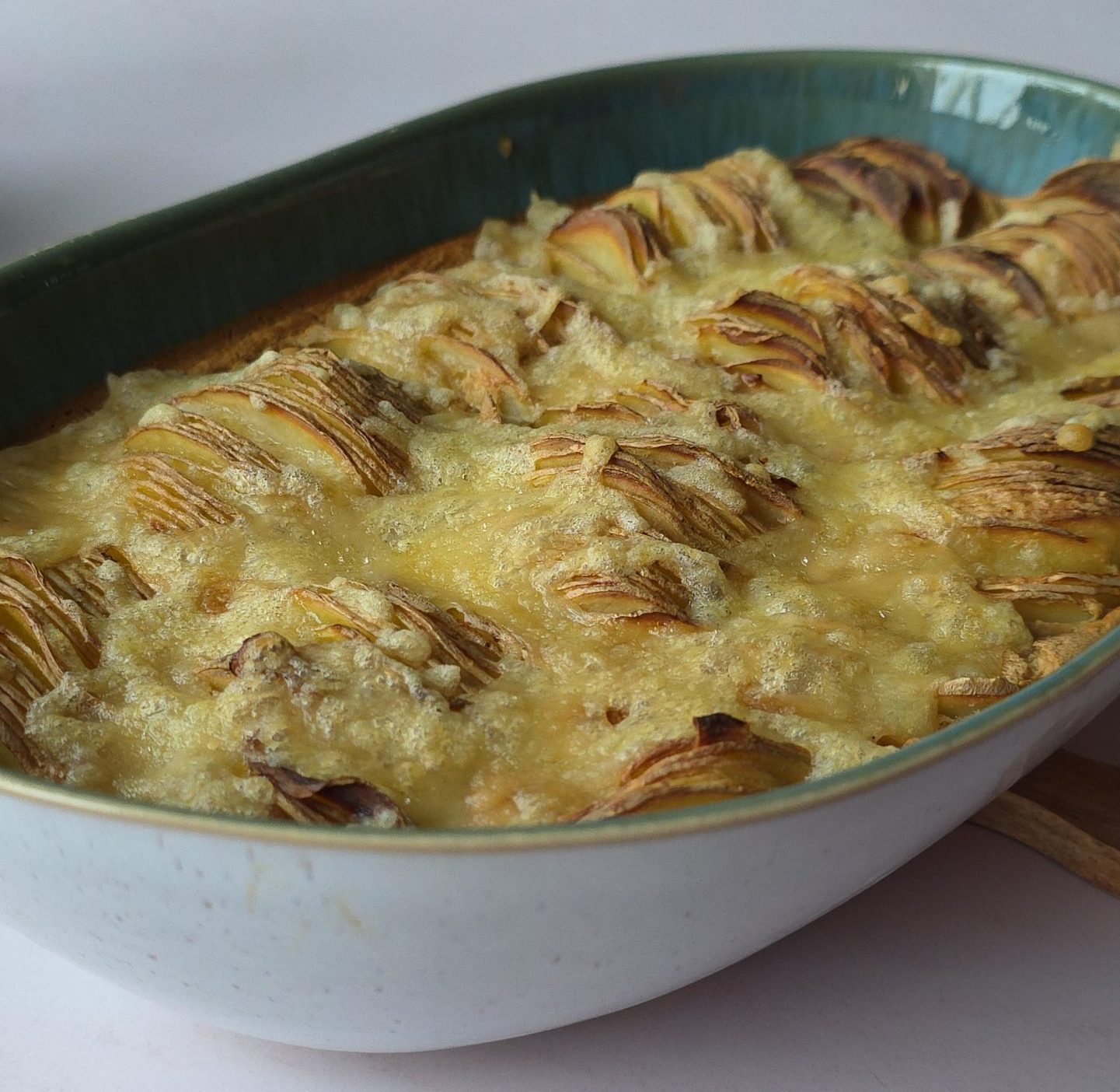 Nahaufnahme von Kartoffelgratin vegan mit goldbrauner Oberfläche, geschichteten Kartoffeln und geschmolzenem veganen Käse in einer Auflaufform.