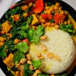 One-Pot Kürbis Curry: buntes Gemüse, Kichererbsen und Tempeh in cremiger Sauce, angerichtet mit Reis, frischem Koriander und Erdnüssen.