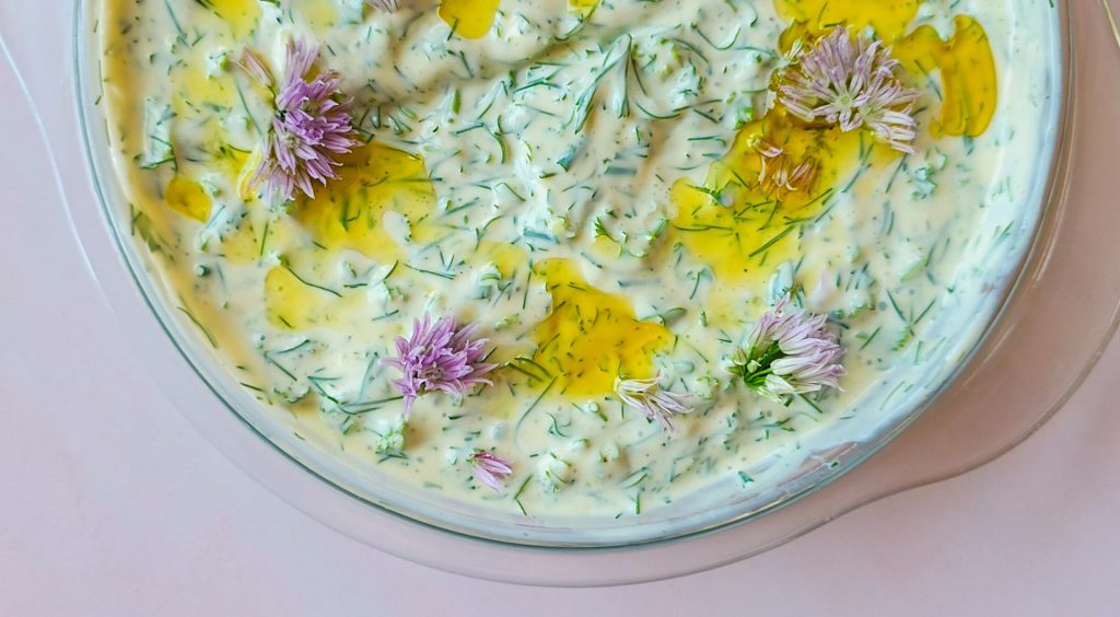 Kräuterquark mit vielen frischen Kräutern, verziert mit Olivenöl und Schnittlauchblüten