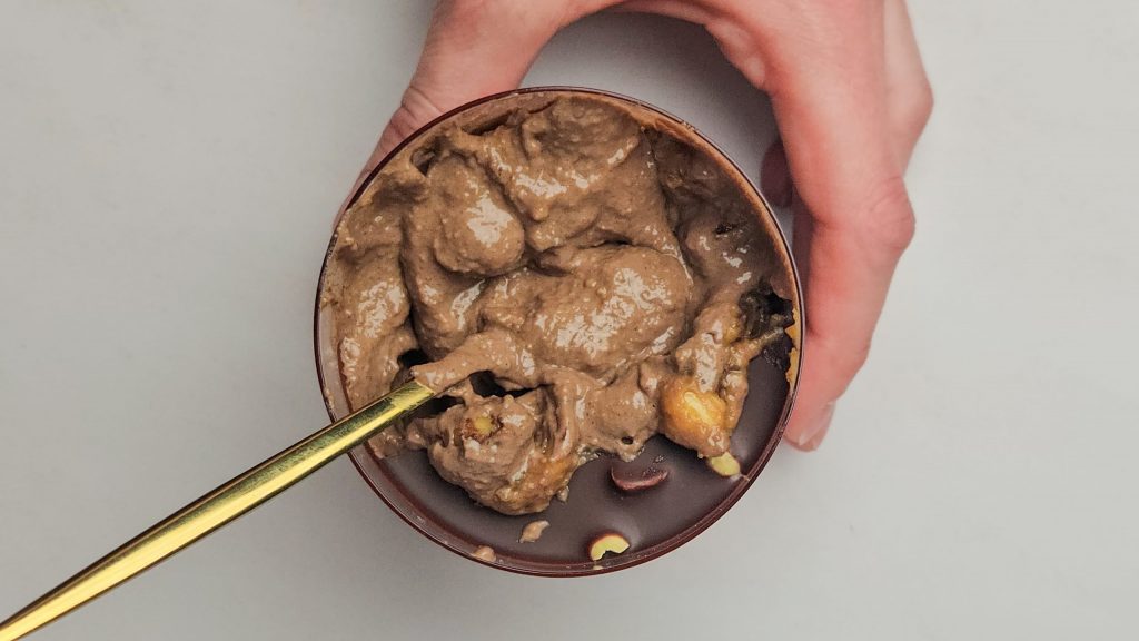Vegane Snickers Overnight Oats von oben mit einer cremigen Schokoschicht, Erdnüssen und einer zerbrochenen Schokoschicht.