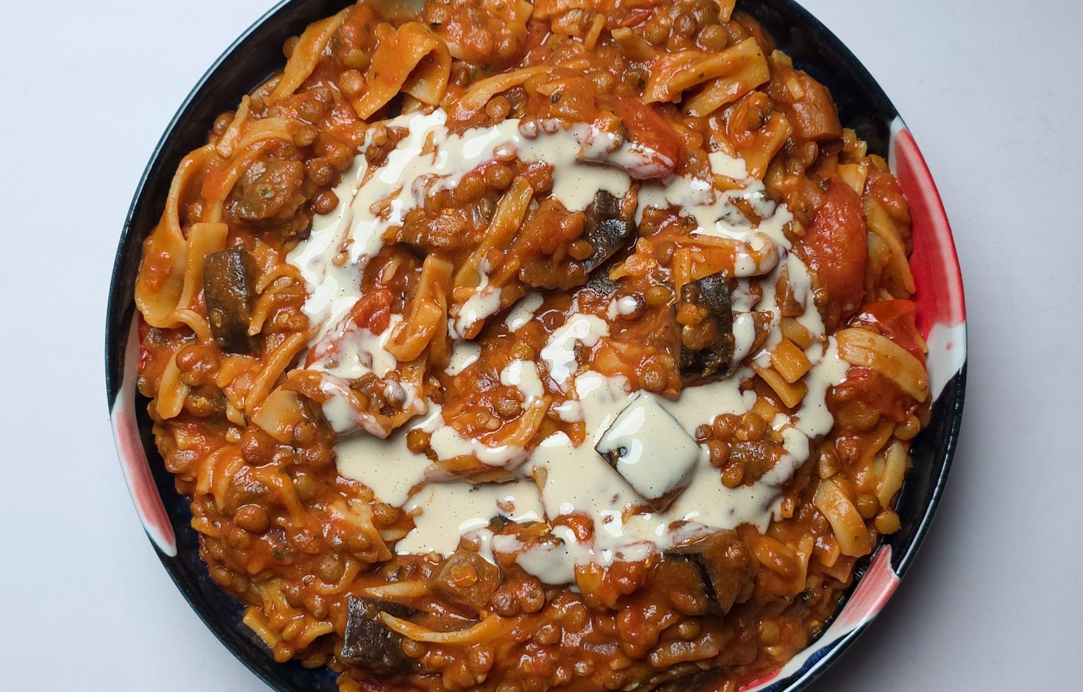 Vegane Lasagnesuppe mit Auberginen, Tomaten und Lasagneplatten in einer Tomatensauce. Daüber verteilt eine cremige weiße Soße.