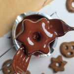 Sternförmiger Lebkuchen wird in geschmolzene Schokolade getaucht.