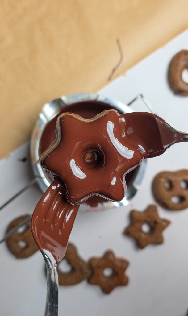 Sternförmiger Lebkuchen wird in geschmolzene Schokolade getaucht.
