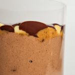 Vegane Snickers Overnight Oats von der Seite mit einer cremigen Schokoschicht, darüber Dattelkaramell mit Erdnüssen und darauf Zartbitterschokolade.