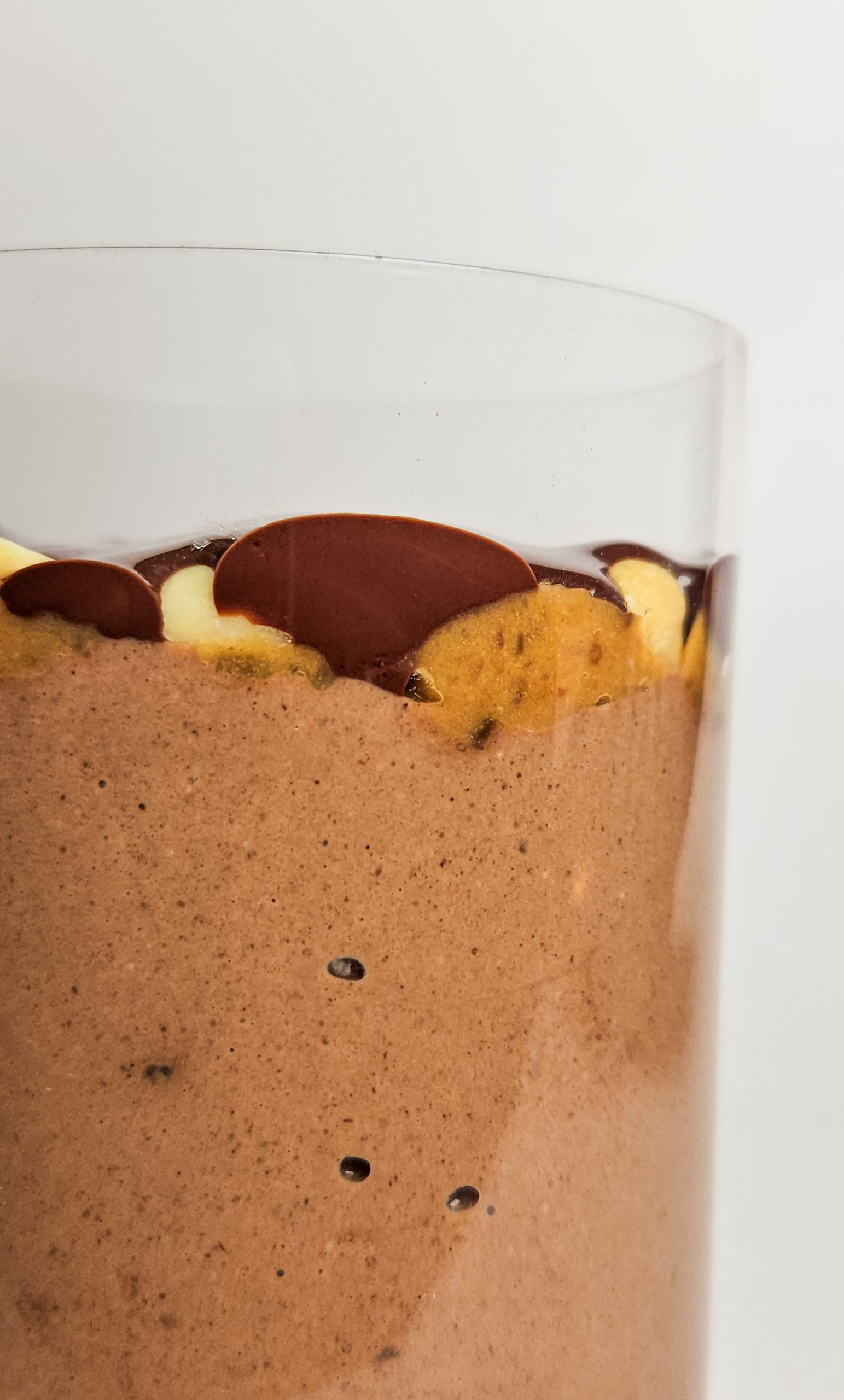 Vegane Snickers Overnight Oats von der Seite mit einer cremigen Schokoschicht, darüber Dattelkaramell mit Erdnüssen und darauf Zartbitterschokolade.