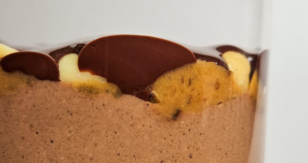 Vegane Snickers Overnight Oats von der Seite mit einer cremigen Schokoschicht, darüber Dattelkaramell mit Erdnüssen und darauf geschmolzene Zartbitterschokolade.