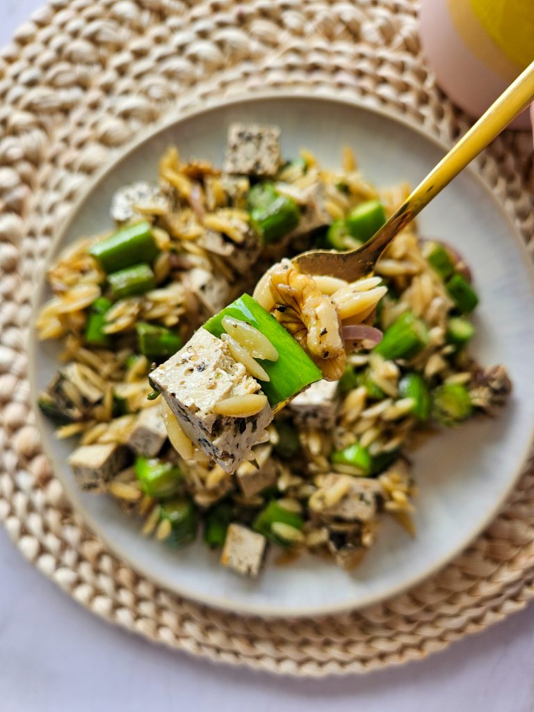 Salat mit Orzo, Spargel, Walnüssen und veganem Feta auf einer Gabel