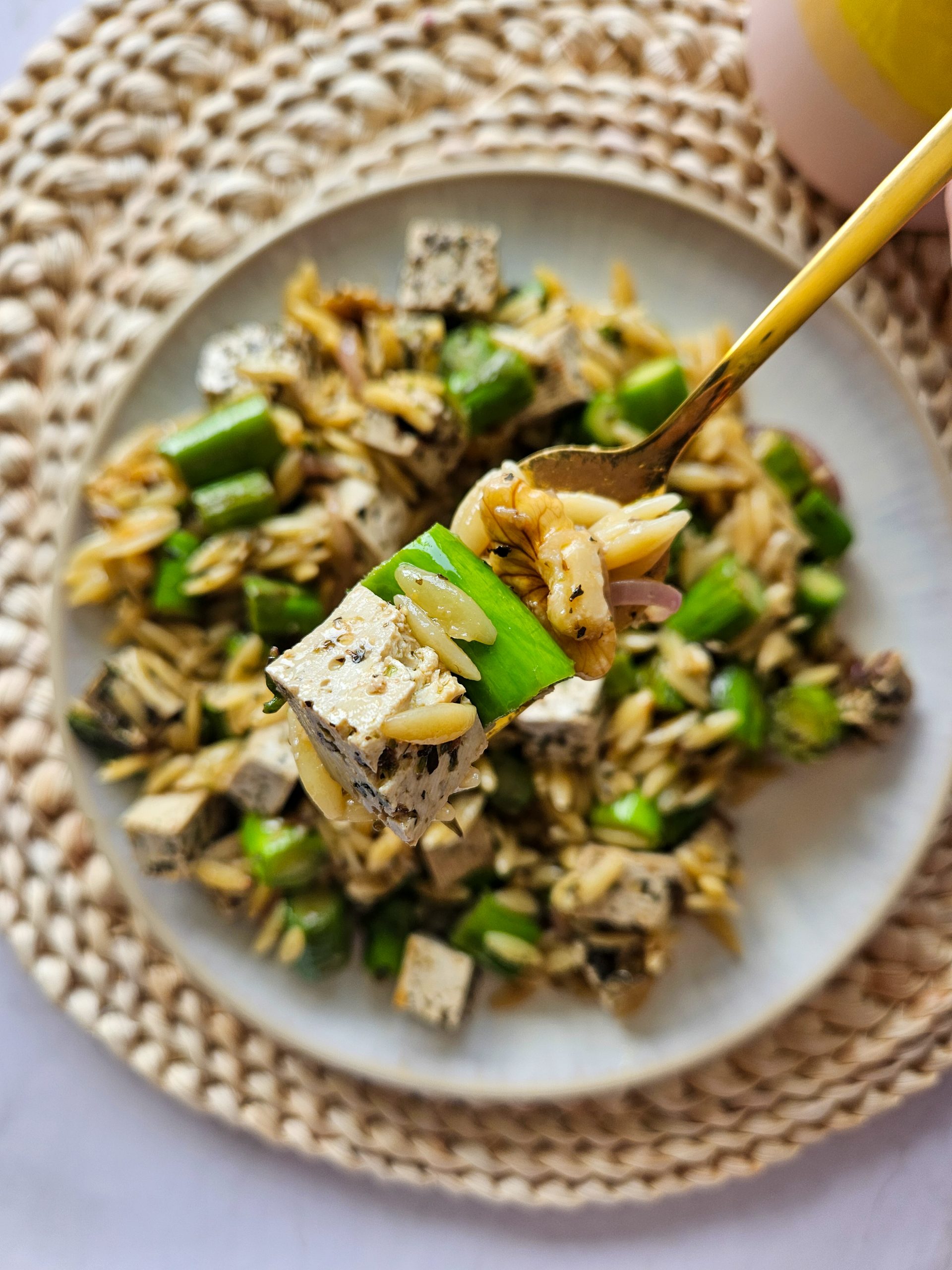 Salat mit Orzo, Spargel, Walnüssen und veganem Feta auf einer Gabel
