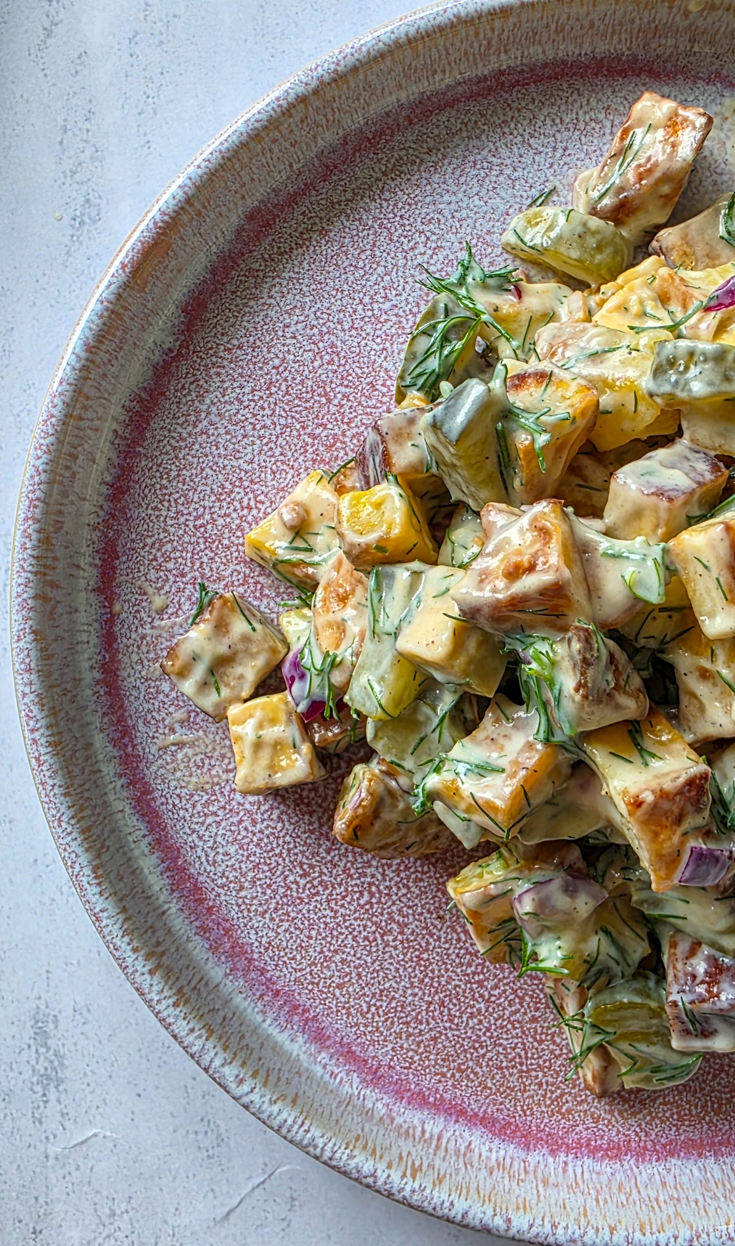 Kartoffelsalat mit Tofu, Gurken, Zwiebeln und einem cremigen Dressing aus Joghurt und Dill.