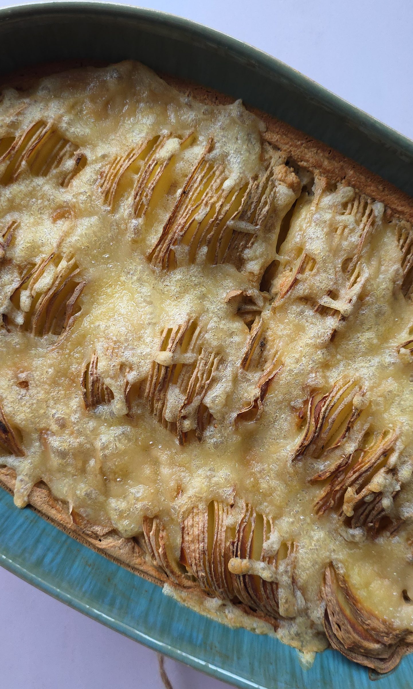 Veganes Kartoffelgratin in einer ovalen Auflaufform mit goldbrauner Käsekruste und fächerförmig geschichteten Kartoffelscheiben.